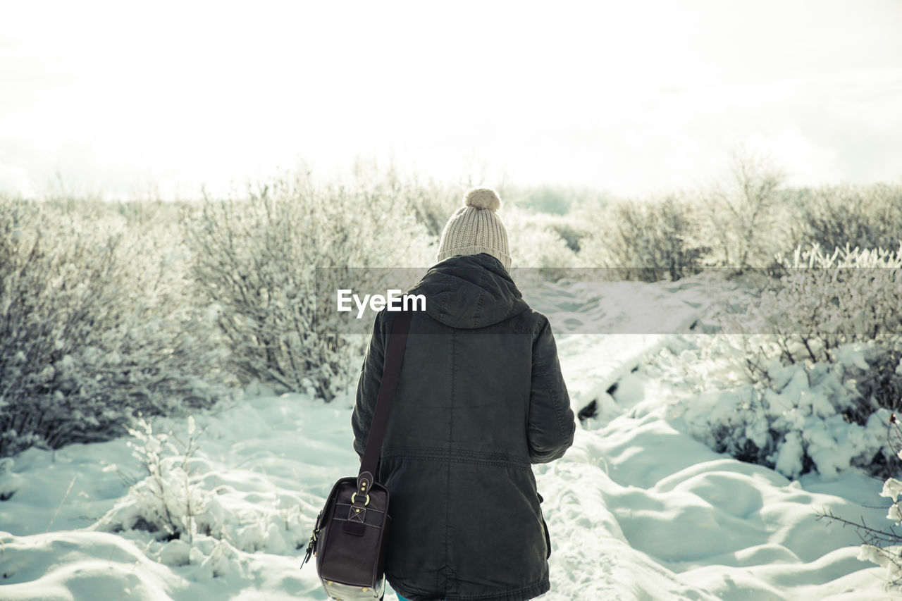 Rear view of woman walking on snow covered field