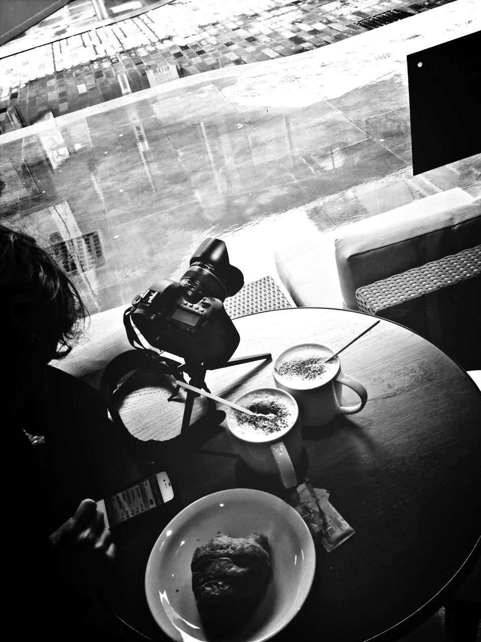 Cropped image of man using phone with coffee breakfast and camera on table in cafe