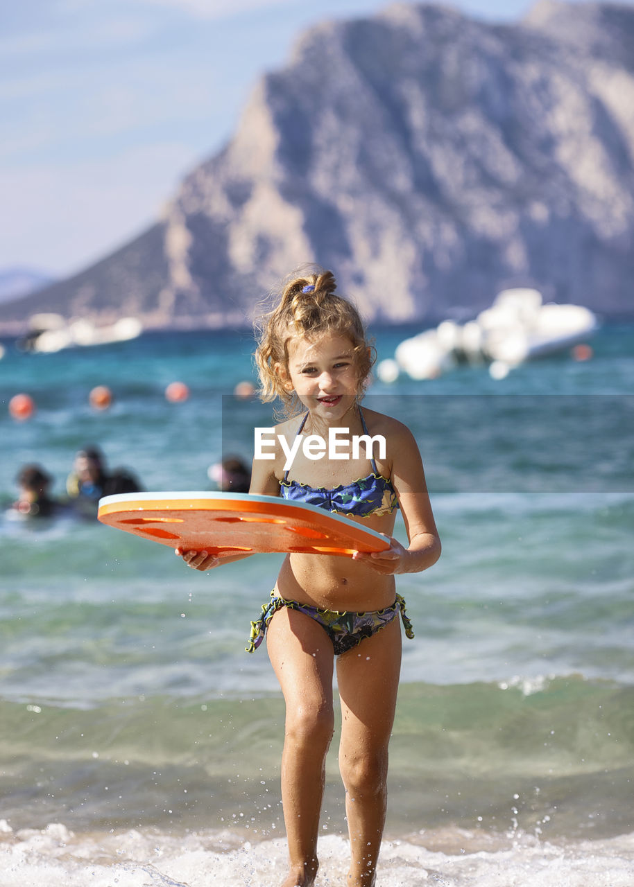 portrait of young woman wearing bikini while standing in sea