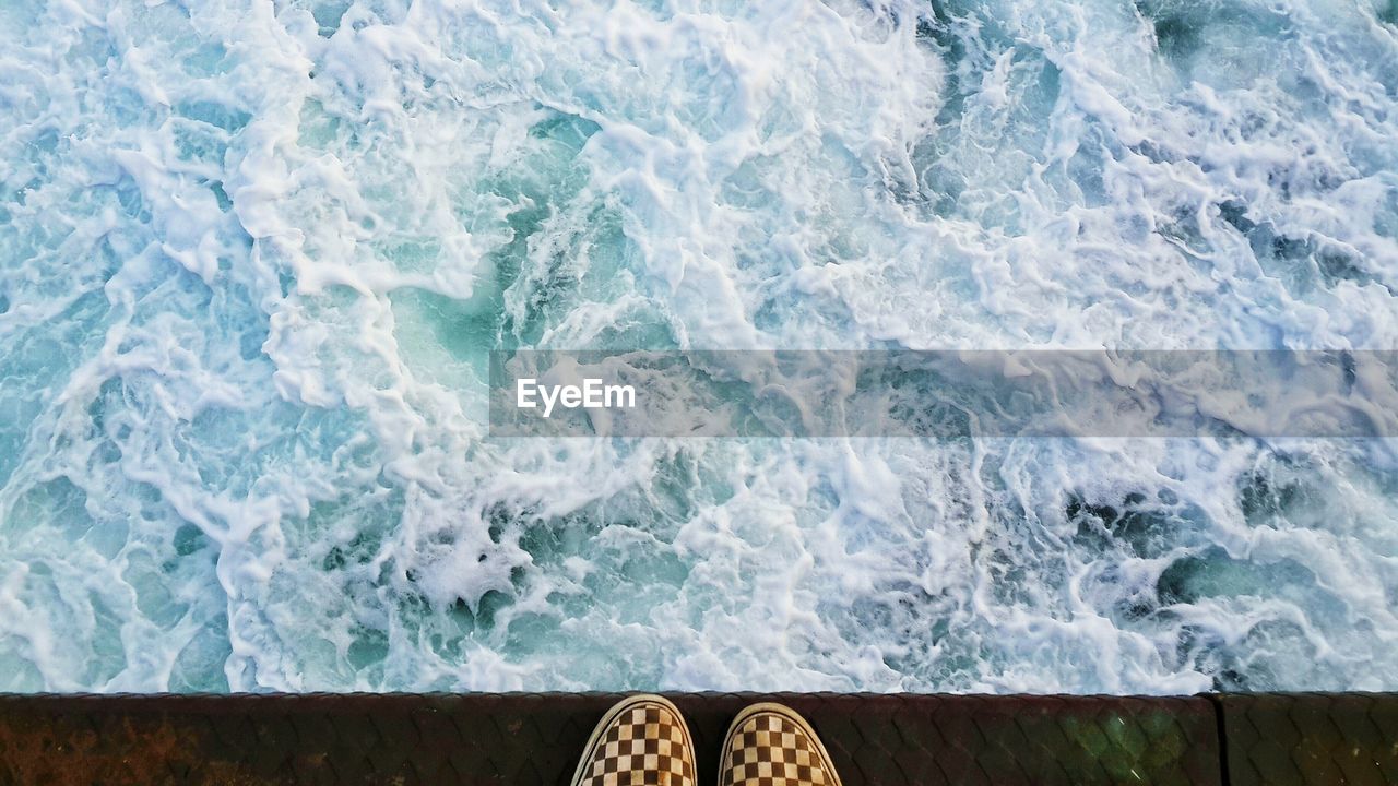 Footwear on edge of pier over sea