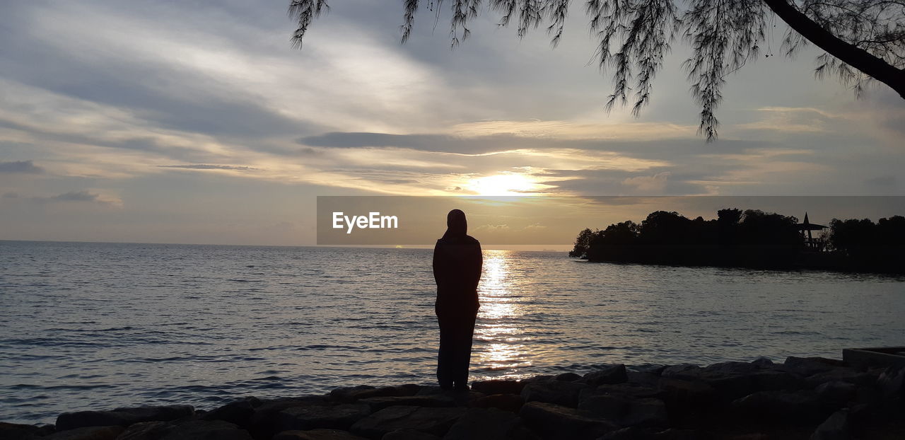 SILHOUETTE OF MAN LOOKING AT SEA