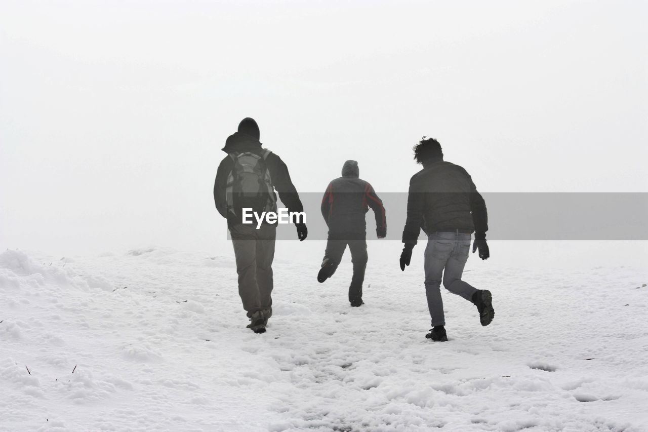 REAR VIEW OF SILHOUETTE PEOPLE WALKING ON SNOW