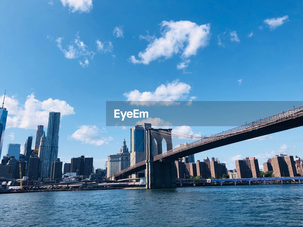 City by river and buildings against sky