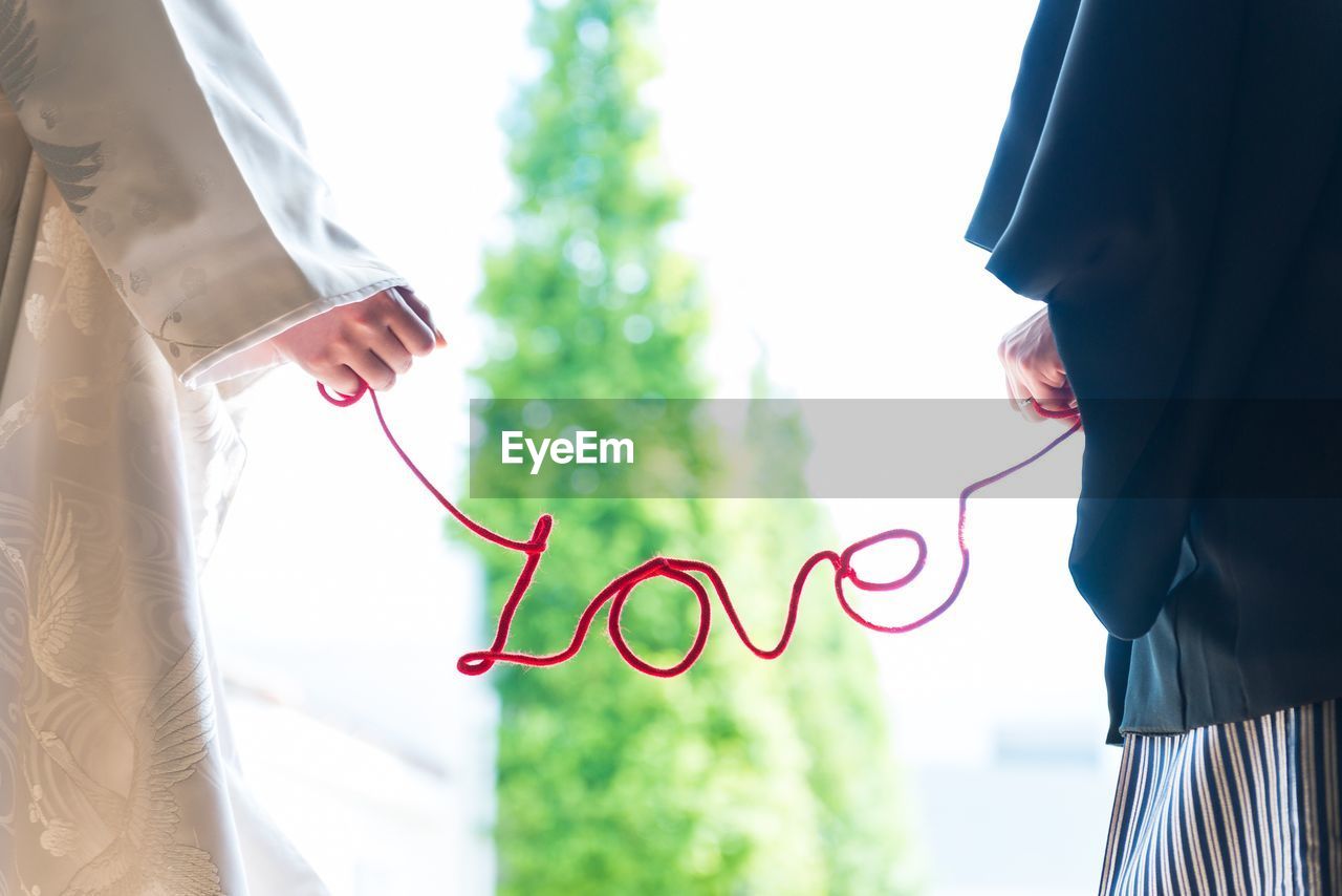 Midsection of couple holding love text while standing outdoors