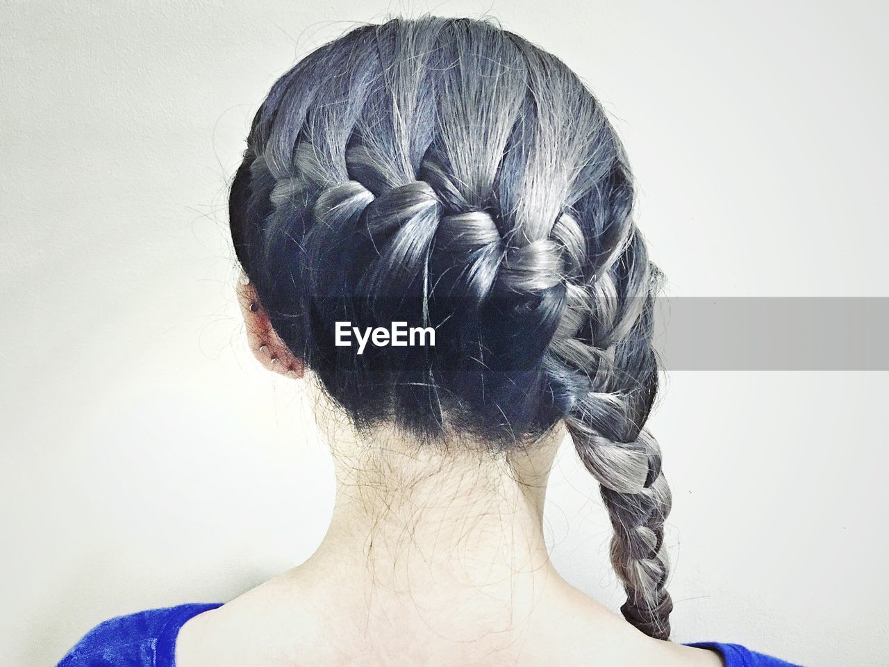 Rear view of woman with braided gray hair against white background