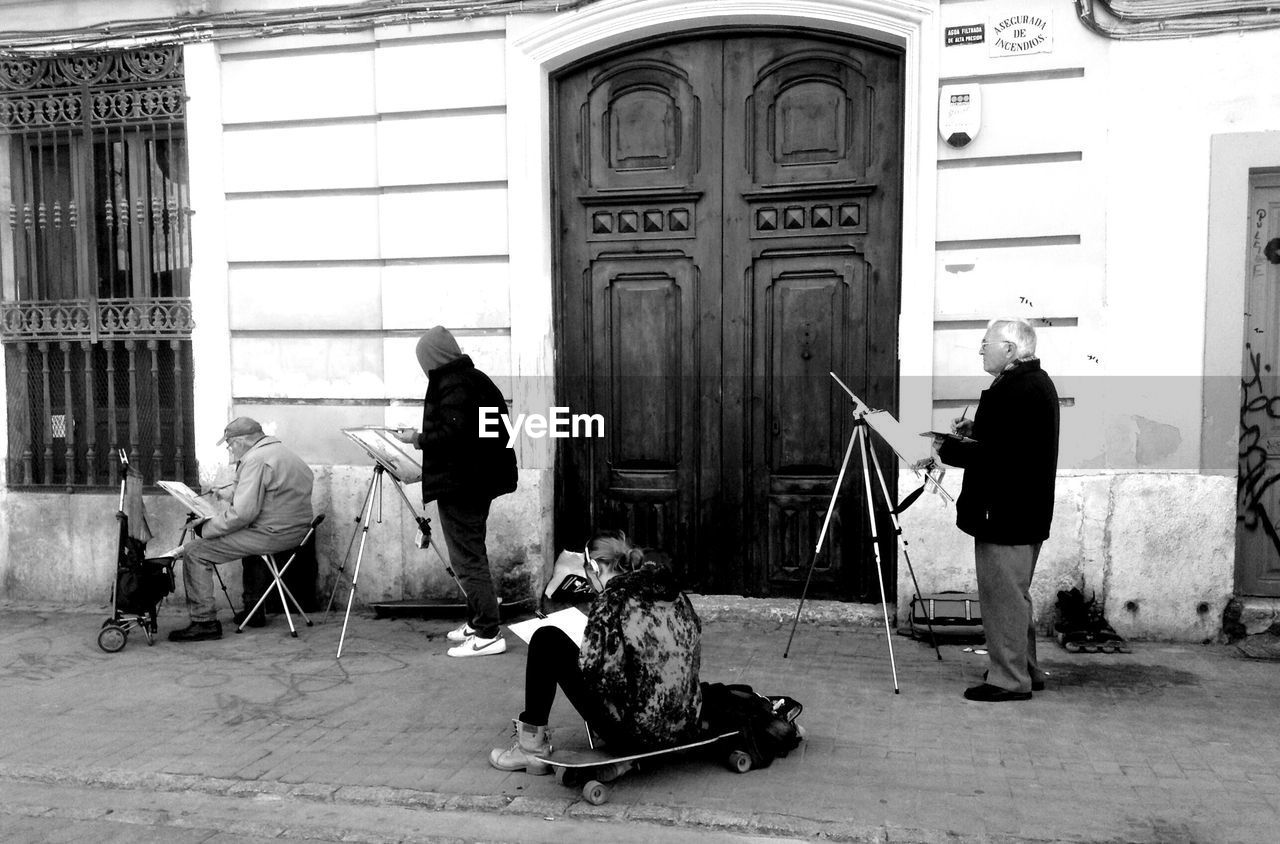 REAR VIEW OF PEOPLE SITTING ON WALL