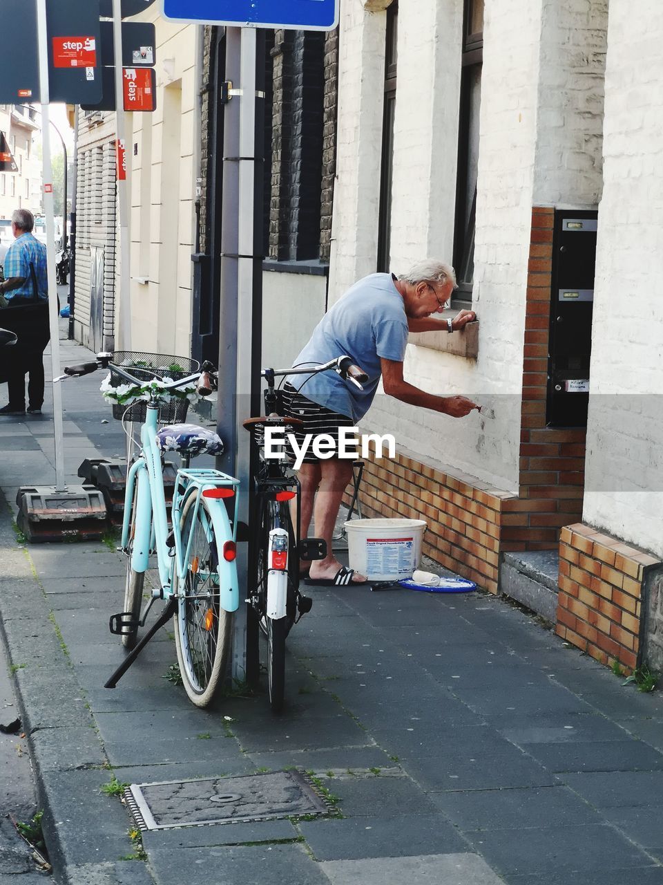 MAN CYCLING ON STREET AMIDST BUILDINGS