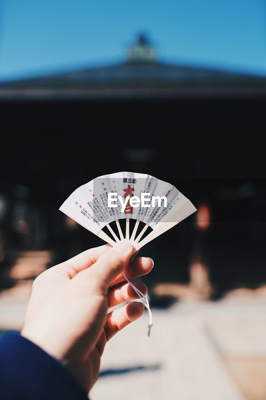 Close-up of hand holding small folding fan