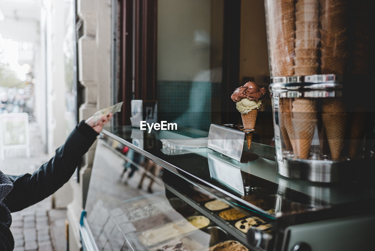 Cropped hand of person paying at ice cream store