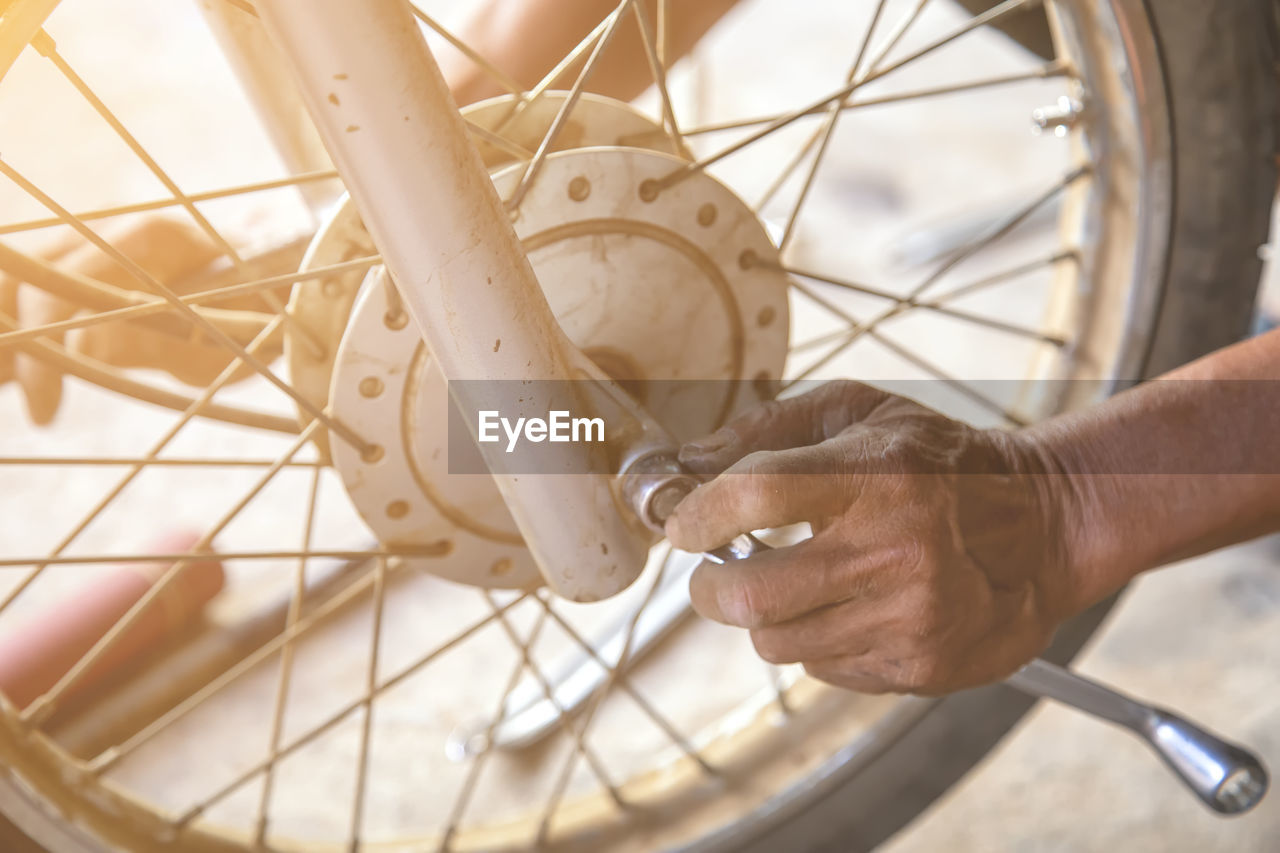 CLOSE-UP OF MAN HAND HOLDING BICYCLE