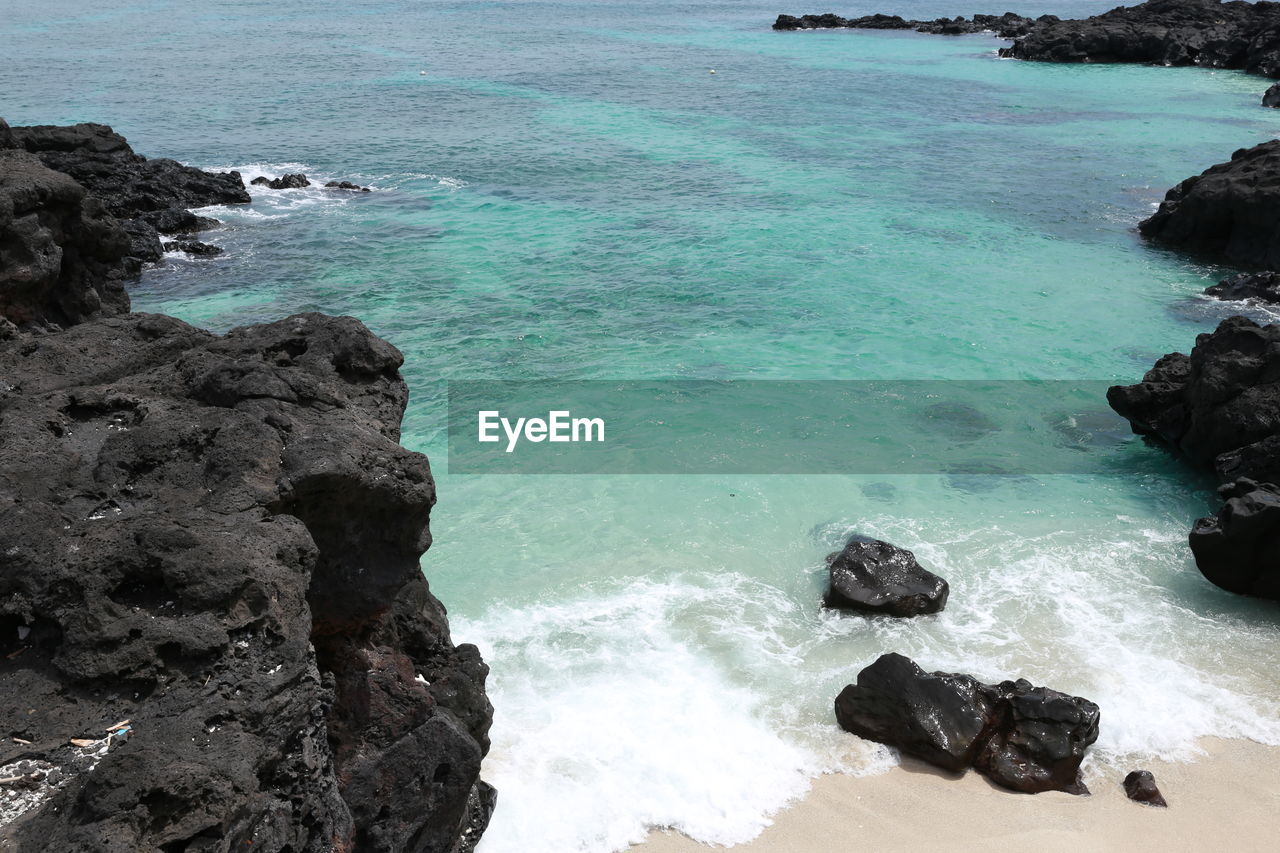 HIGH ANGLE VIEW OF ROCKS AT SEA