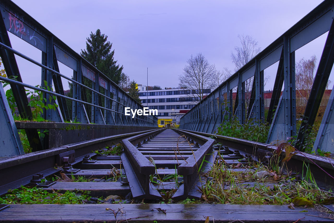 Bridge over railroad tracks against sky