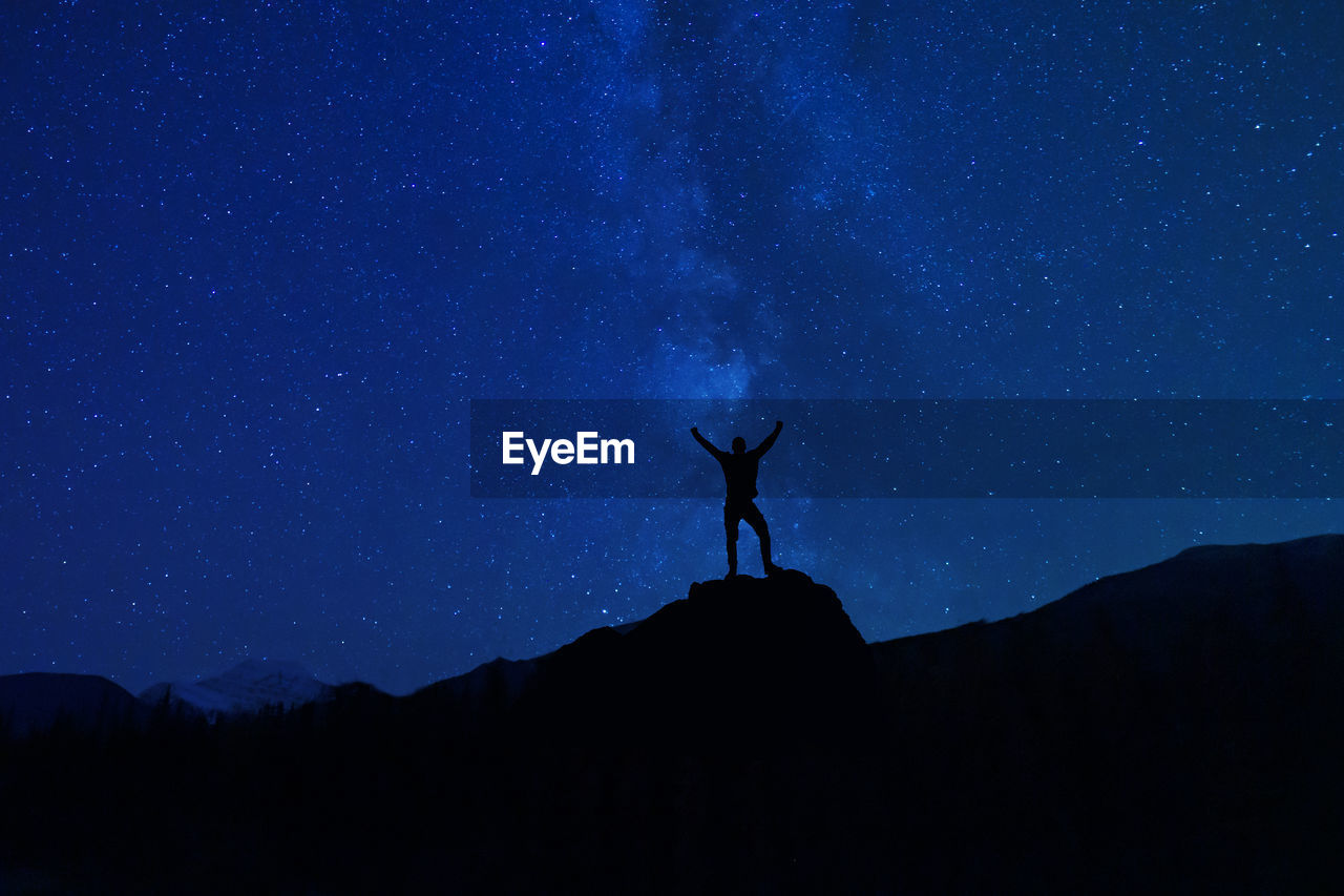 Low angle view of silhouette person standing against sky at night