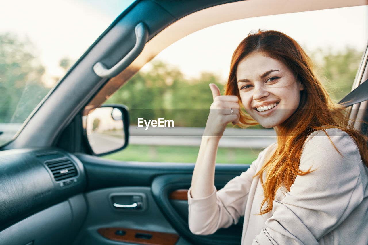 Portrait of smiling woman gesturing while sitting in car