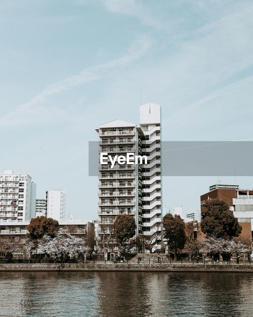 Buildings by river against sky