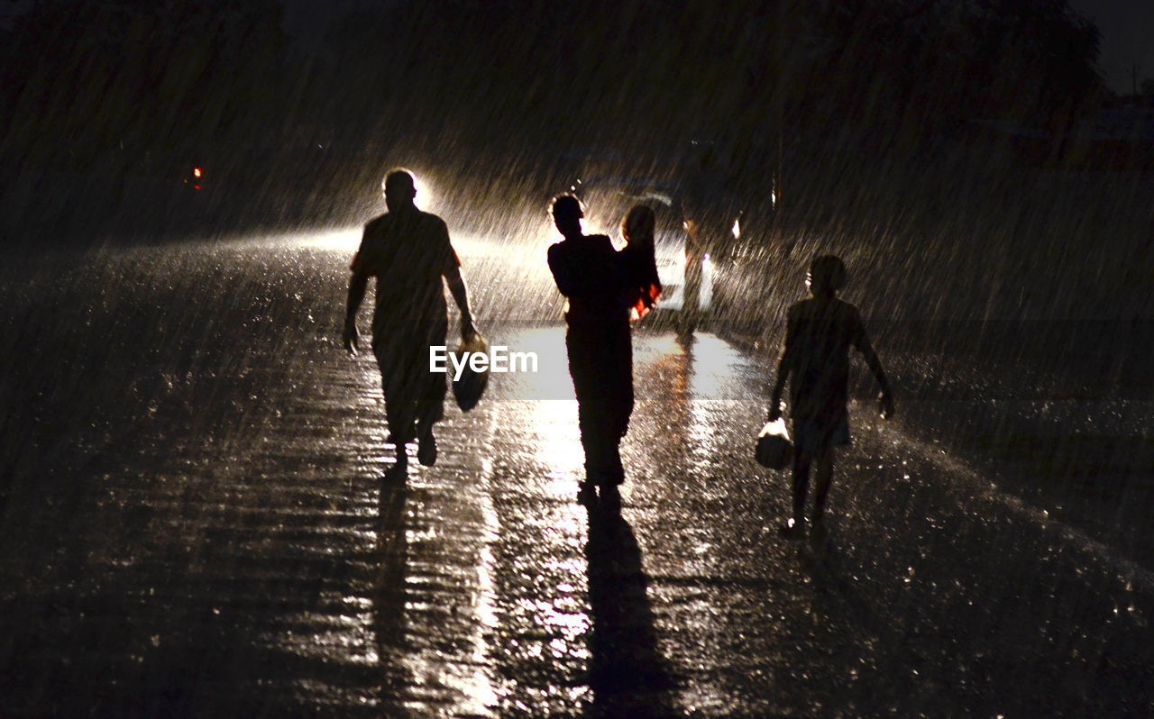 PEOPLE ON WET STREET AT NIGHT