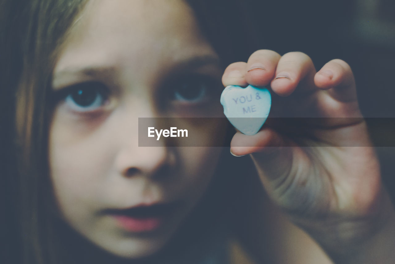 Close-up portrait of girl holding candy saying "you and me"