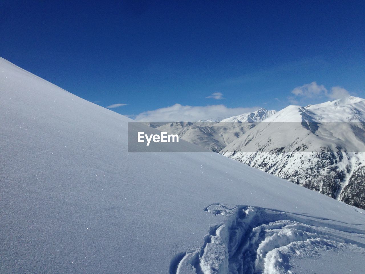 Scenic view of snowcapped mountains against blue sky