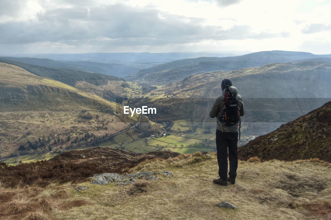 REAR VIEW OF MAN LOOKING AT MOUNTAINS