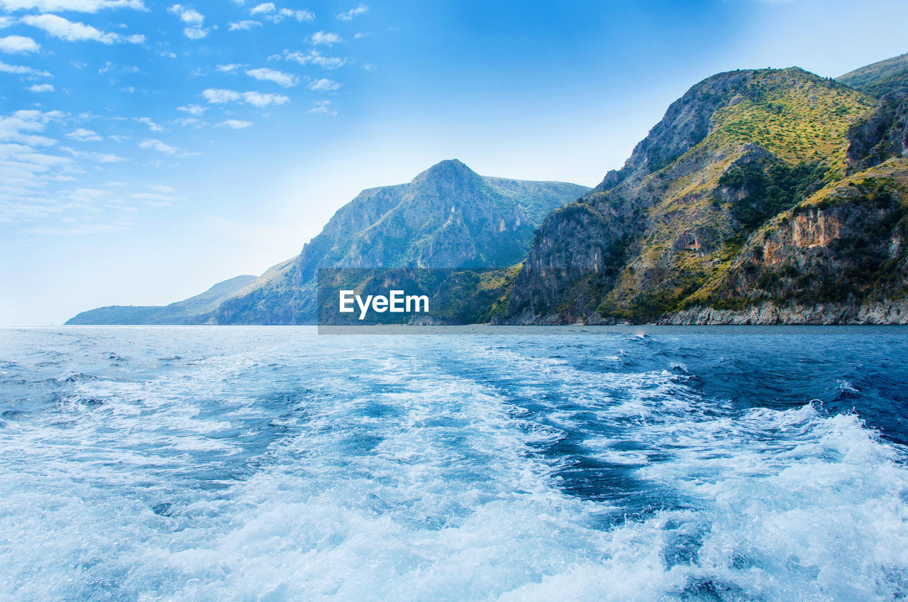 SCENIC VIEW OF SEA BY MOUNTAINS AGAINST SKY