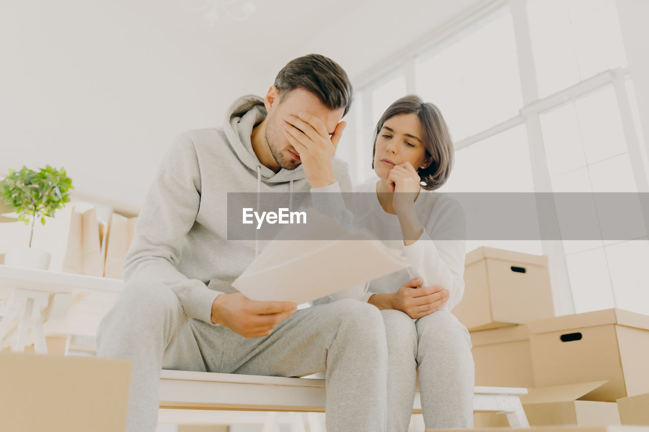 Woman sitting with stressed man by boxes at home