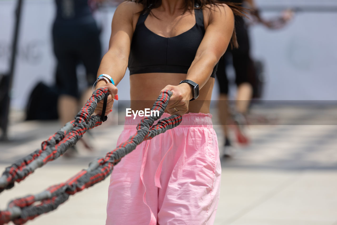 Girl having fitness workout with rope in an outdoor gym.