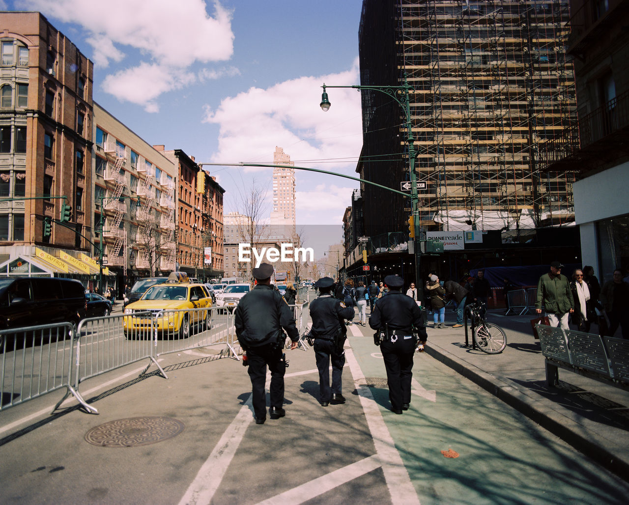 Rear view of police officers walking on sidewalk in city