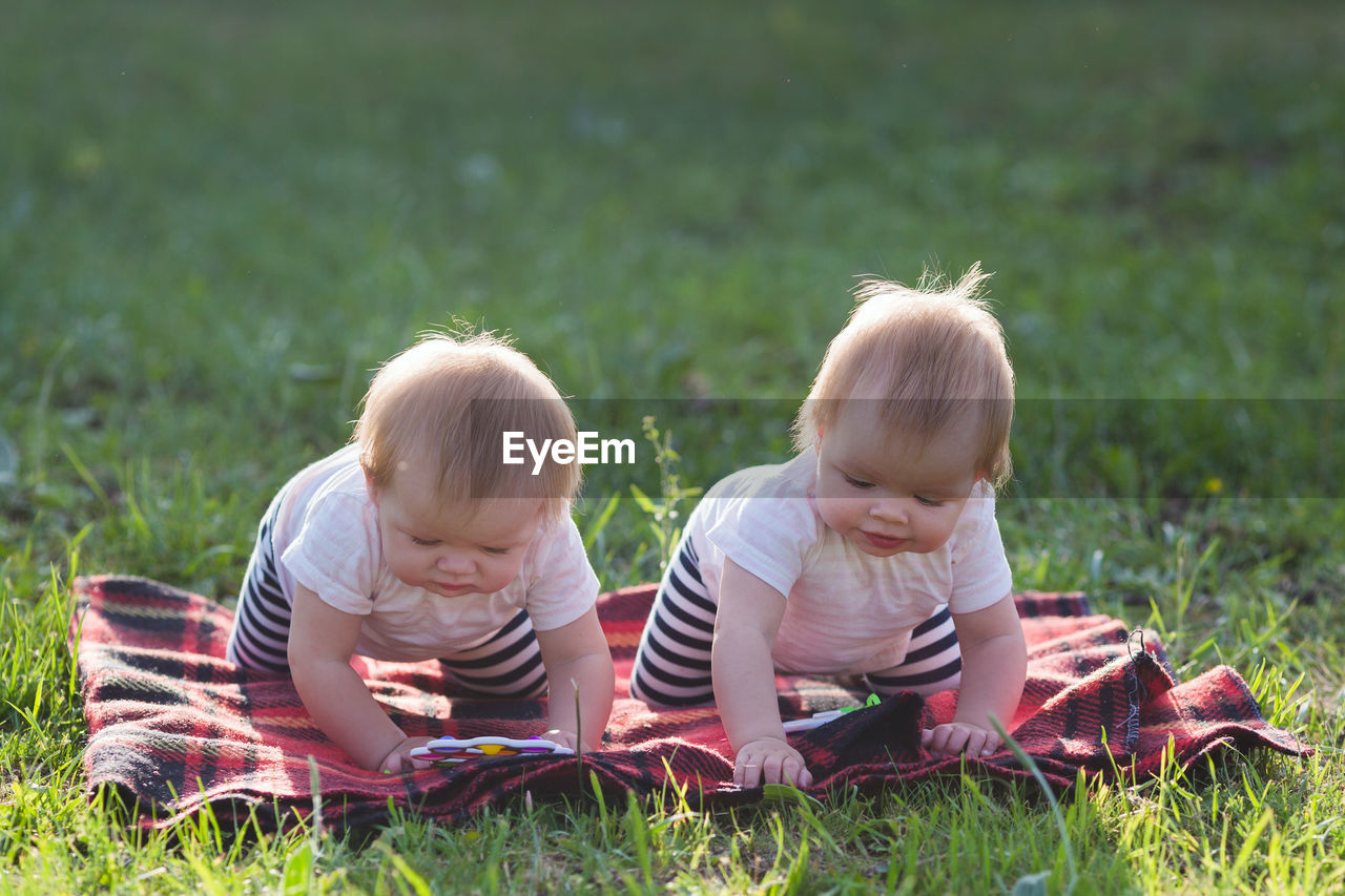 Two children of 6 months crawl a blanket in the square.