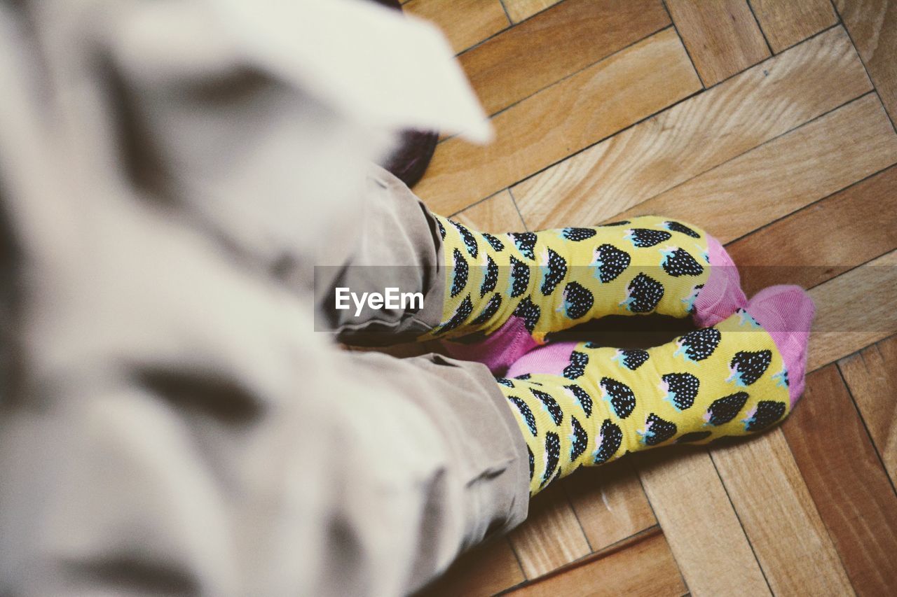 Low section of person wearing socks standing on hardwood floor
