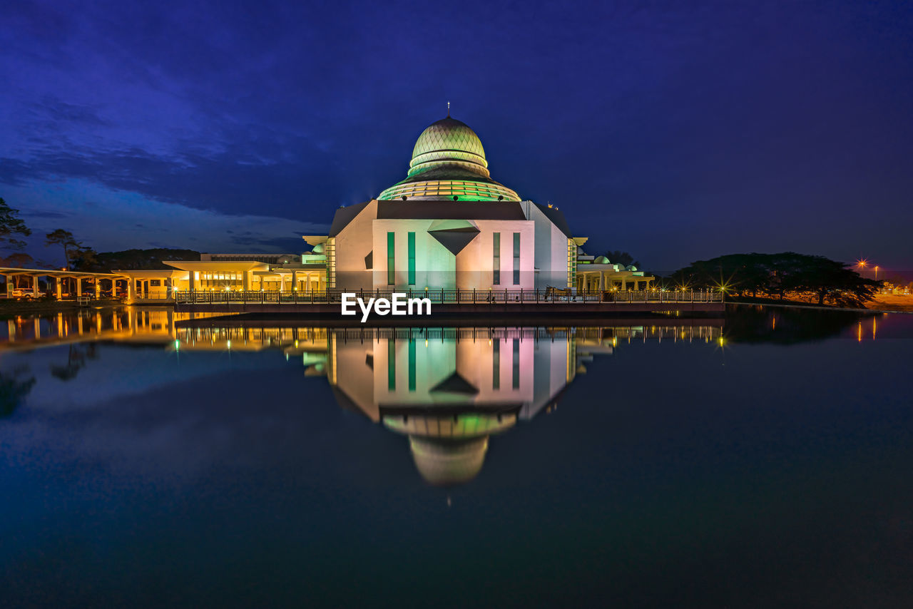 REFLECTION OF ILLUMINATED BUILDING IN LAKE