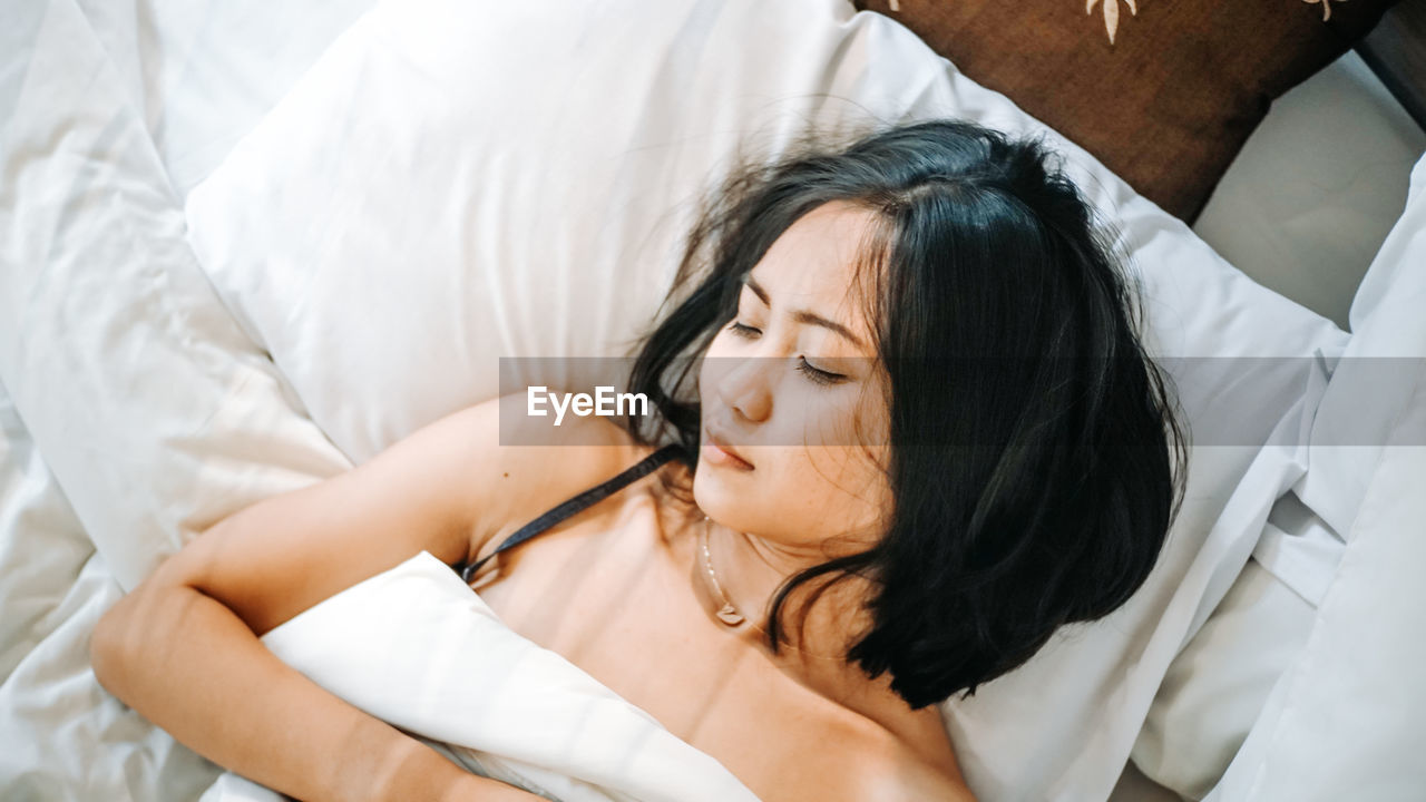 High angle view of woman sleeping on bed