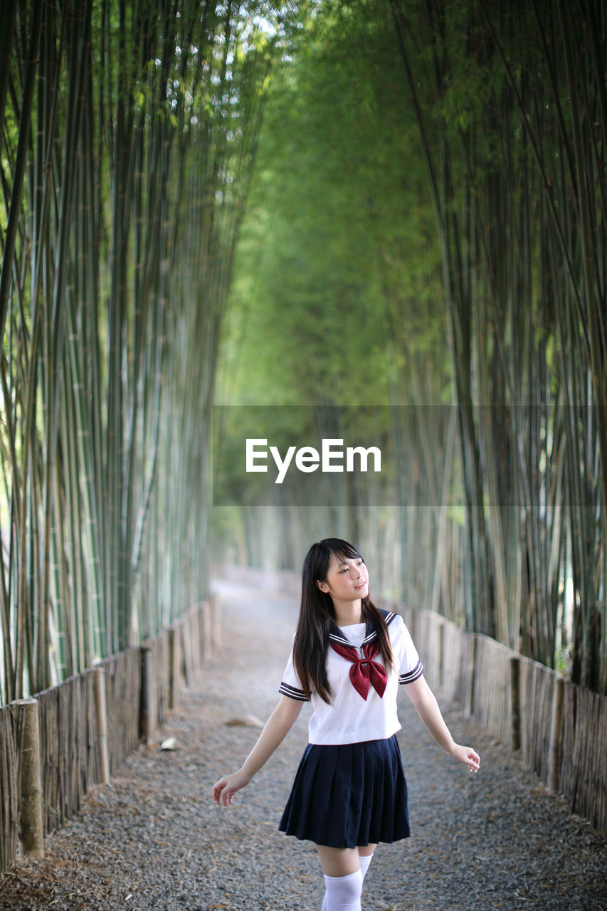 Young woman looking away while standing amidst bamboo groove