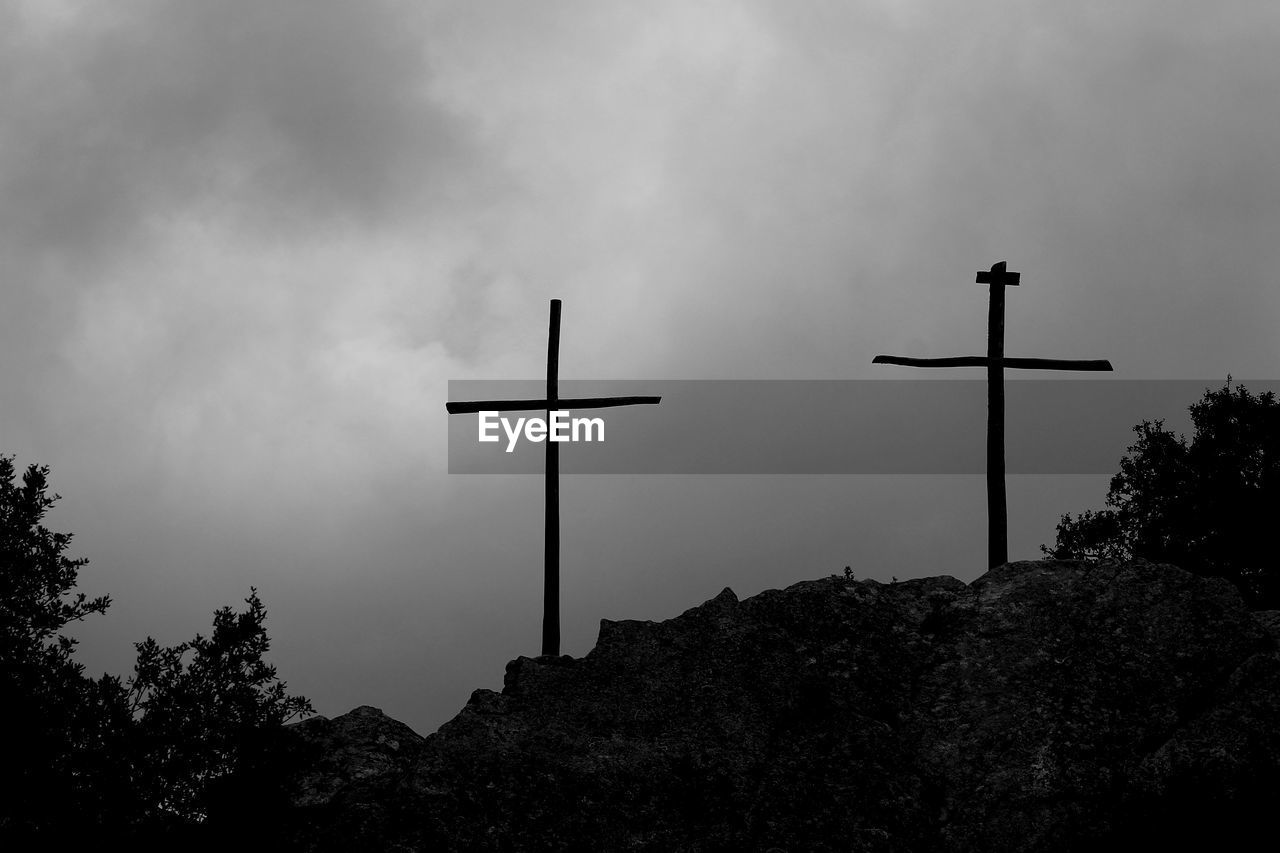 Low angle view of silhouette cross against sky