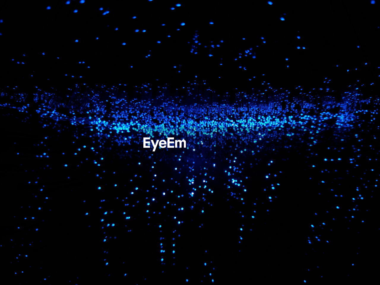 DEFOCUSED IMAGE OF ILLUMINATED LIGHTS AGAINST BLACK BACKGROUND AT NIGHT