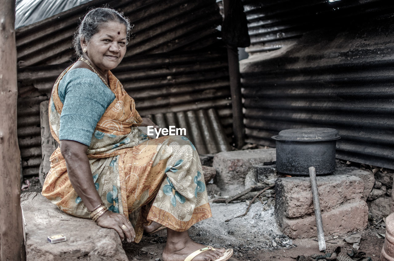 Portrait of smiling woman preparing food on stove in village