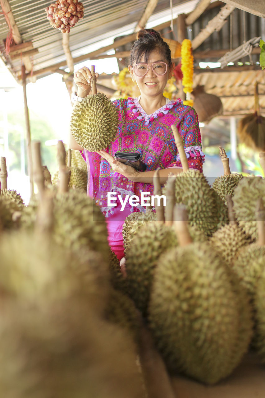 Portrait of smiling woman holding durian at store