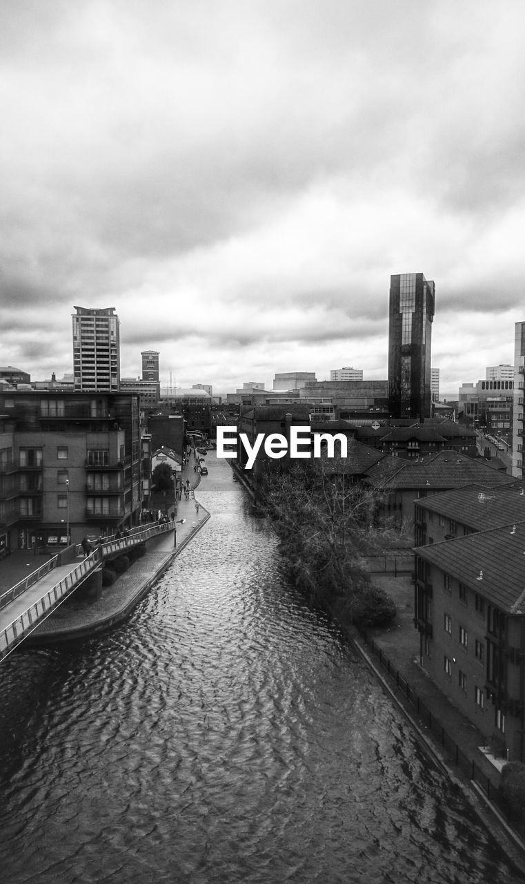 High angle view of river amidst buildings against cloudy sky