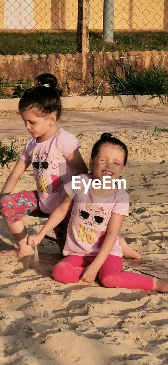 Siblings playing on sand at beach