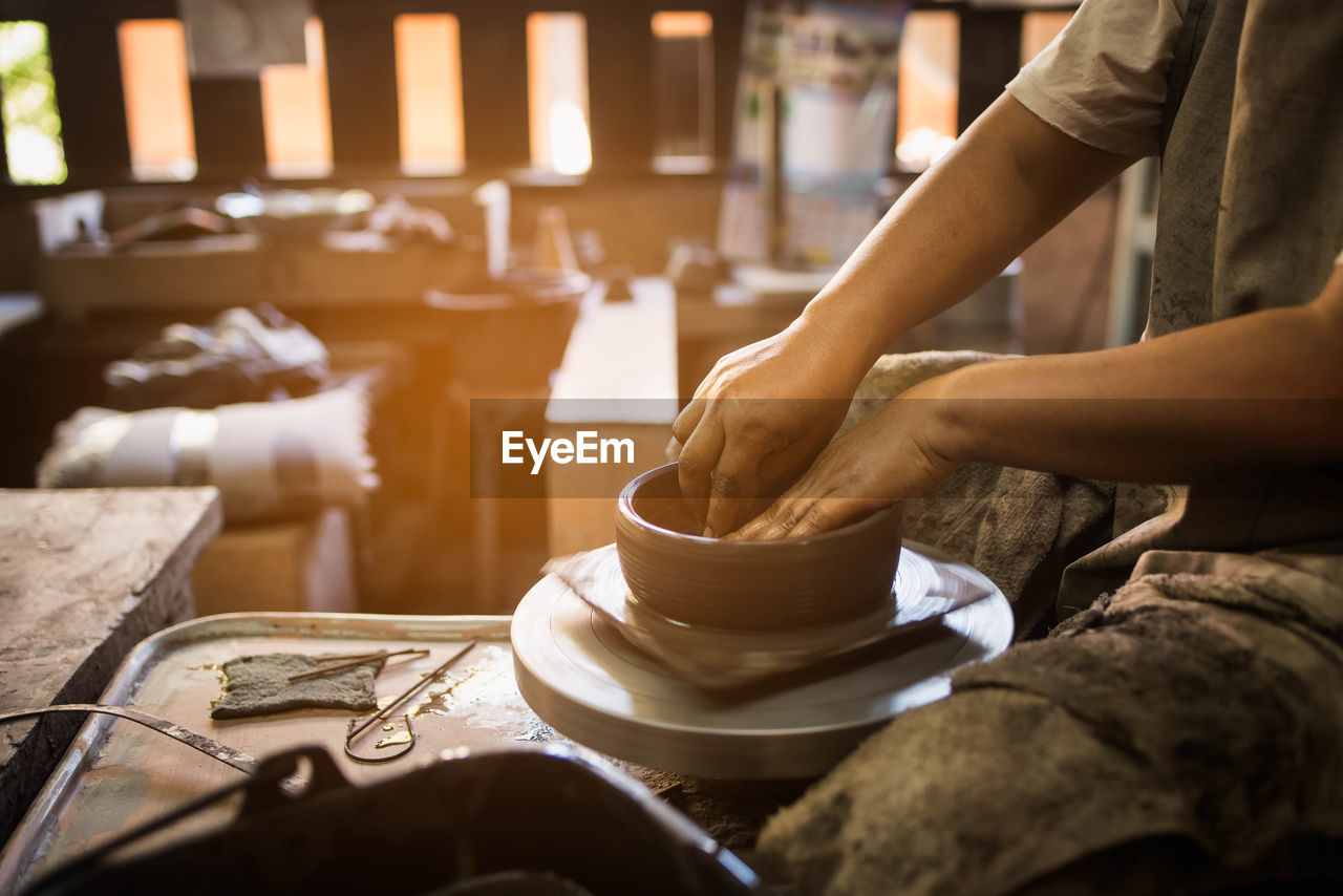 Midsection of potter making pottery at workshop