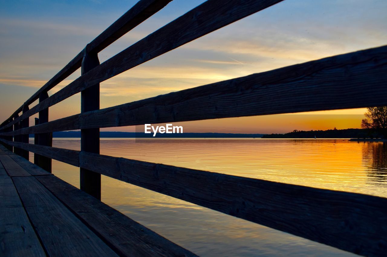 Pier over lake against sky during sunset