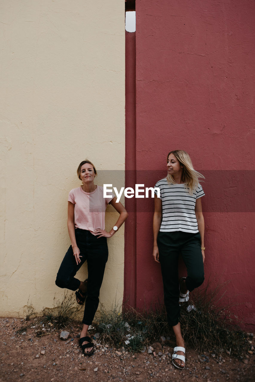 Cheerful friends standing against wall