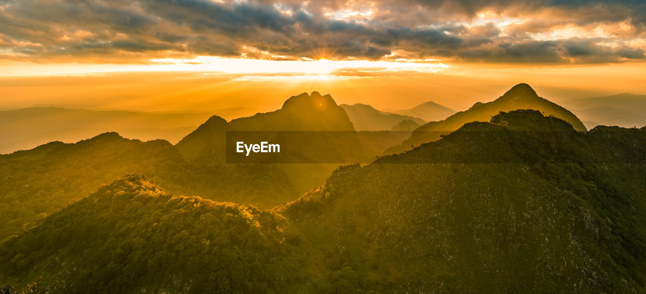 Panoramic beautiful mountain peaks topped with sky, cloud and blast sun, and camera flares
