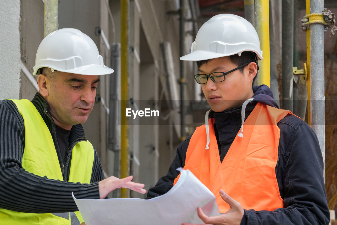 Engineers discussing while standing at construction site