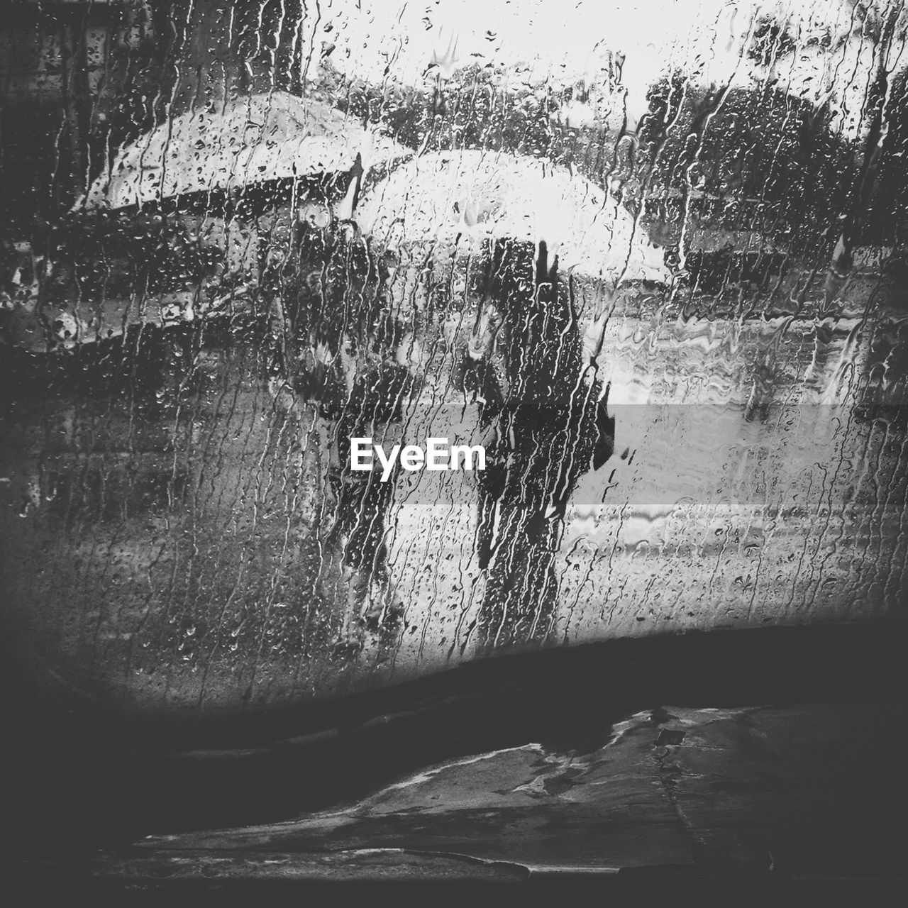 People walking with umbrella in rain viewed through window