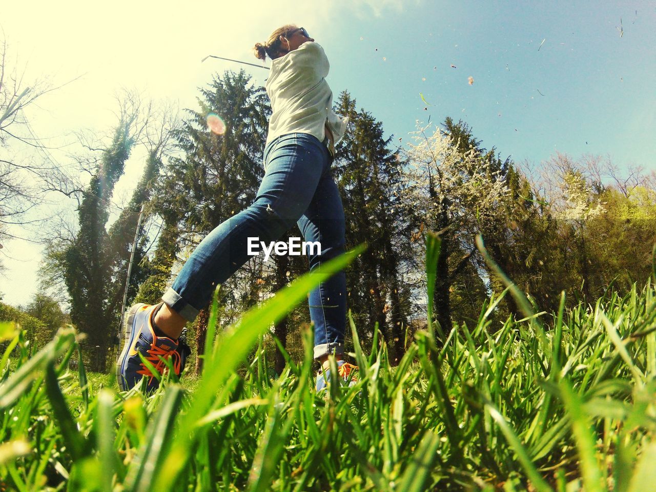 Low angle view of woman playing golf by trees