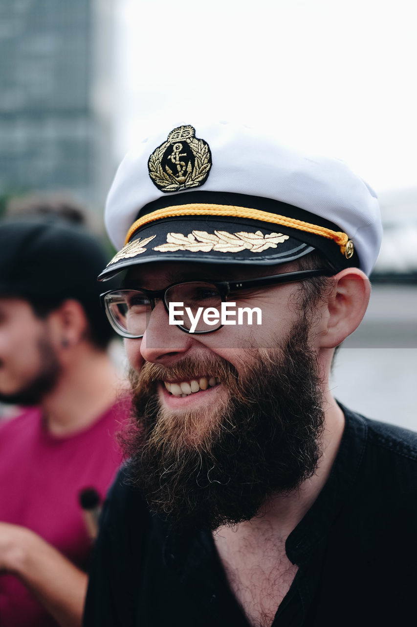 Smiling bearded man wearing eyeglasses and cap in city