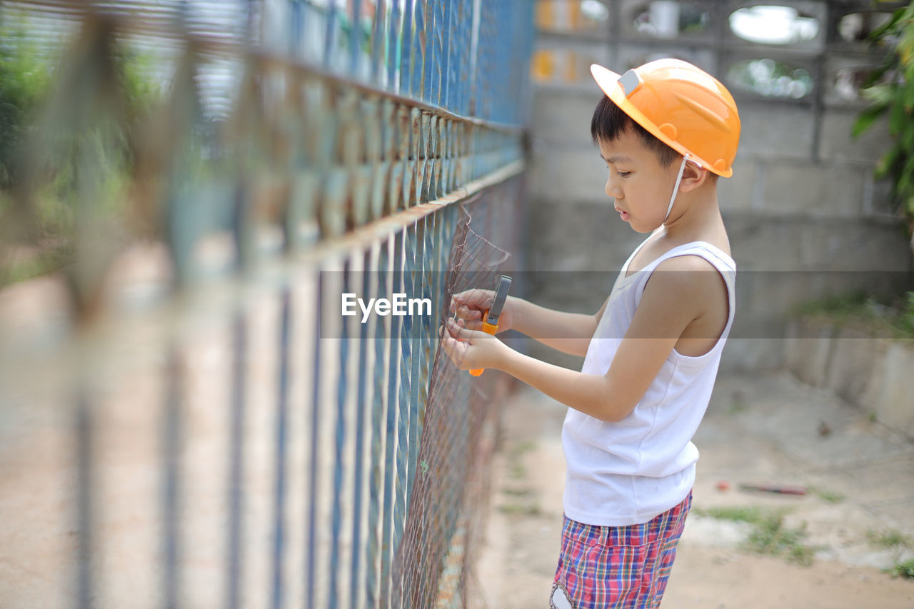 Side view of boy cutting fence