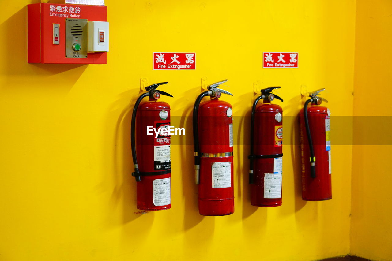 fire extinguisher, yellow, emergency equipment, red, accidents and disasters, wall - building feature, no people, communication, security, protection, text, drink