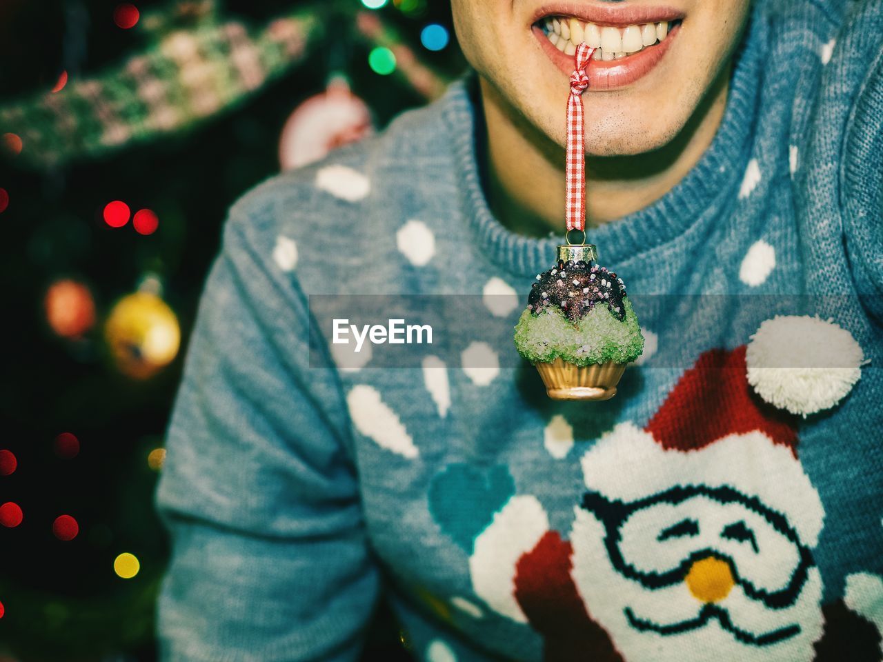Midsection of man holding christmas decoration in mouth