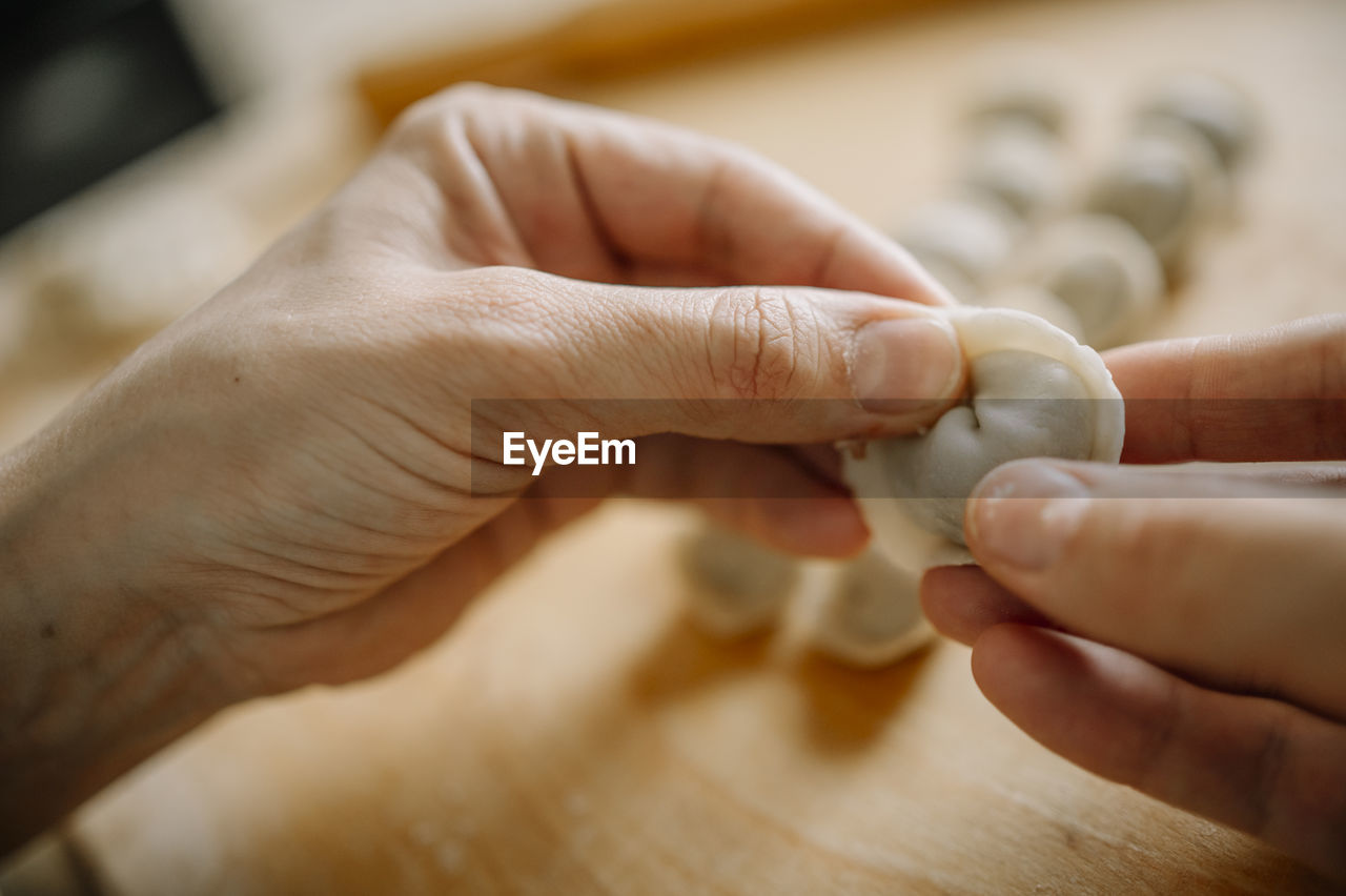 Hands of woman molding dumpling in kitchen at home